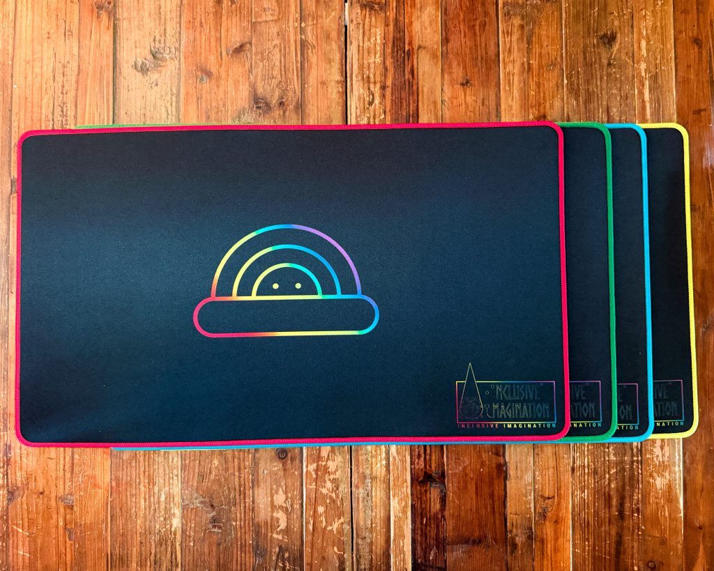 All Playmat Color Options on Table with Chasing Rainbows Logo and Inclusive Imagination Logo in Rainbow Gradient