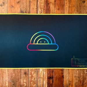 Yellow Playmat on Table with Chasing Rainbows Logo and Inclusive Imagination Logo in Rainbow Gradient